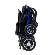 A folded electric wheelchair shown from the side against a plain white background. The wheelchair features a black fabric seat and frame, a blue metal frame section, and black wheels with silver hubcaps.