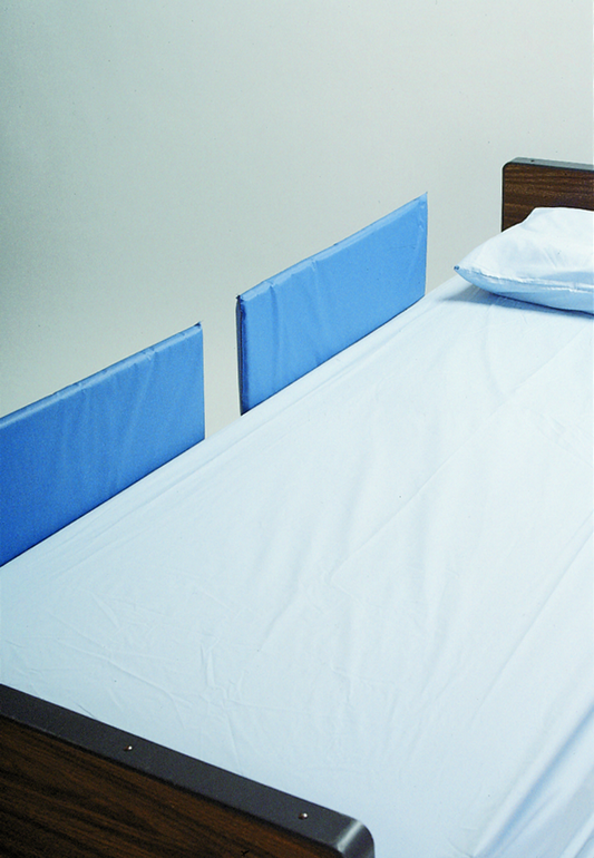 Bed with blue side rails against a plain wall
