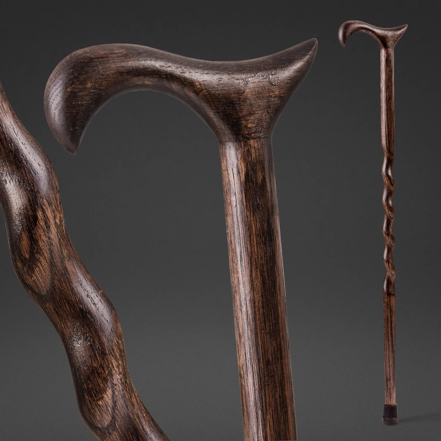 Three wooden walking sticks with different handles on a dark background