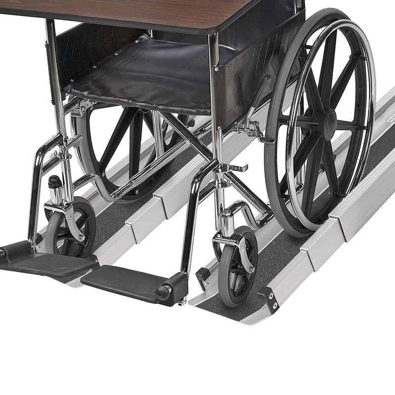 A wheelchair with a dark wood-look top and black seat, shown partially folded over a set of silver metal ramp rails with dark textured surfaces, on a white background.