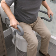 Person using a grab bar for assistance while using a toilet in a bathroom.