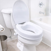 A white plastic toilet training seat insert installed on a white toilet in a bright, clean bathroom next to a bathtub.