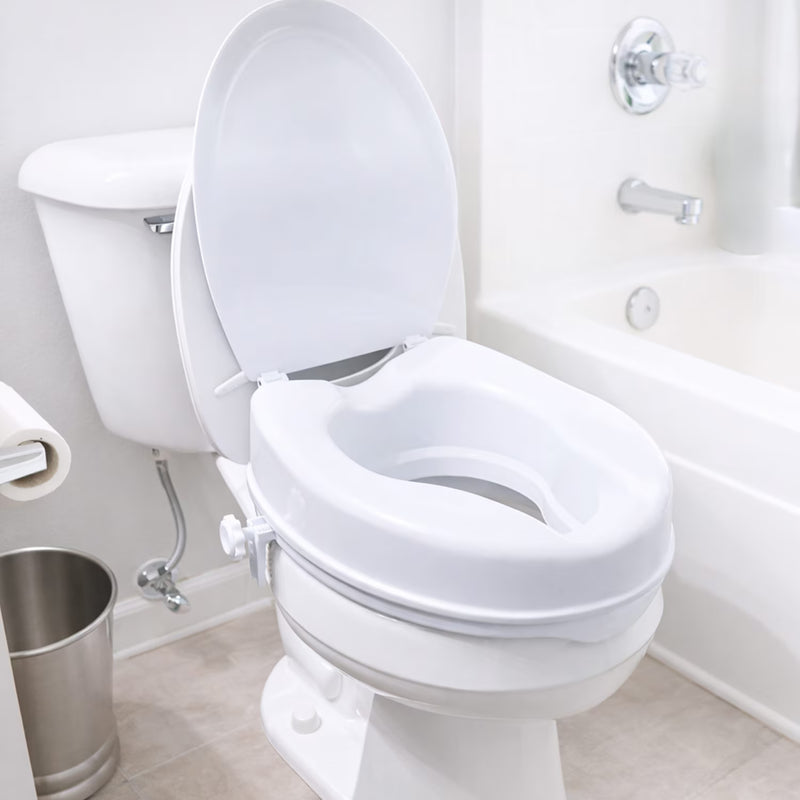 A white plastic toilet training seat insert installed on a white toilet in a bright, clean bathroom next to a bathtub.