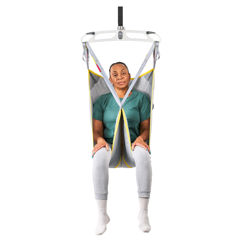A person seated in a suspended medical or transfer chair with a white frame, gray fabric sling, yellow trim, and black straps, shown against a plain white background.