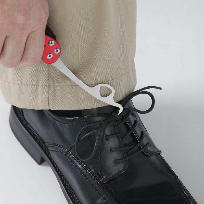 Person using a shoe lace cutter on a black shoe with a plain background