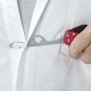 A close-up of a hand holding a red and black pocket tool against a white button-down shirt, demonstrating its use on a button.