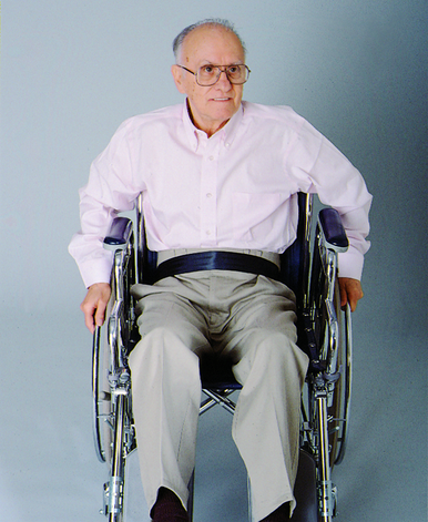 Man in a wheelchair wearing glasses against a plain background