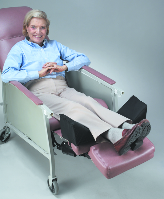 Person sitting in a medical chair with adjustable leg rest on a plain background