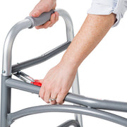 Person using a silver walker with red handle on a white background