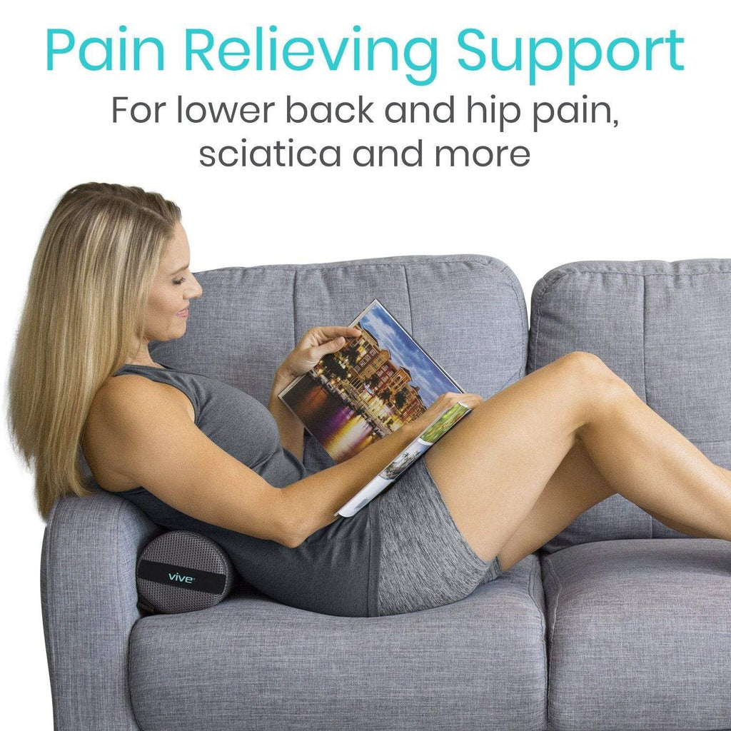 Woman reading a magazine on a couch with pain relieving support for lower back and hip pain.