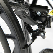 Close-up of a wheelchair brake lever and caliper on a blurred background