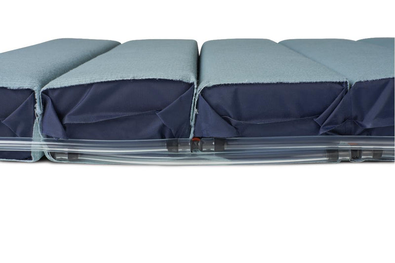 A close-up side view of a padded seat or cushion with a light blue-gray fabric top and a dark navy fabric side panel, resting on a clear plastic base against a white background.