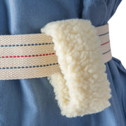 Close-up of a cream-colored waist wrap or belt with a soft, textured fleece-like underside, worn around a blue garment.