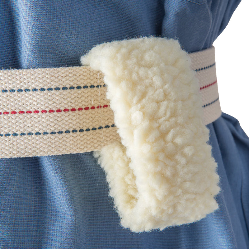 Close-up of a cream-colored waist wrap or belt with a soft, textured fleece-like underside, worn around a blue garment.