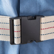 Close-up of a woven belt with a cream-colored strap featuring red and blue stripes, secured with a black plastic buckle over a light blue textured fabric.