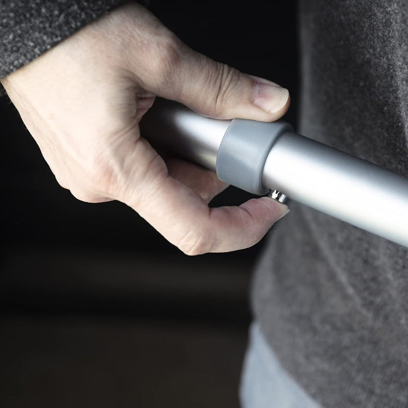 Hand holding a silver and gray cylindrical object against a dark background