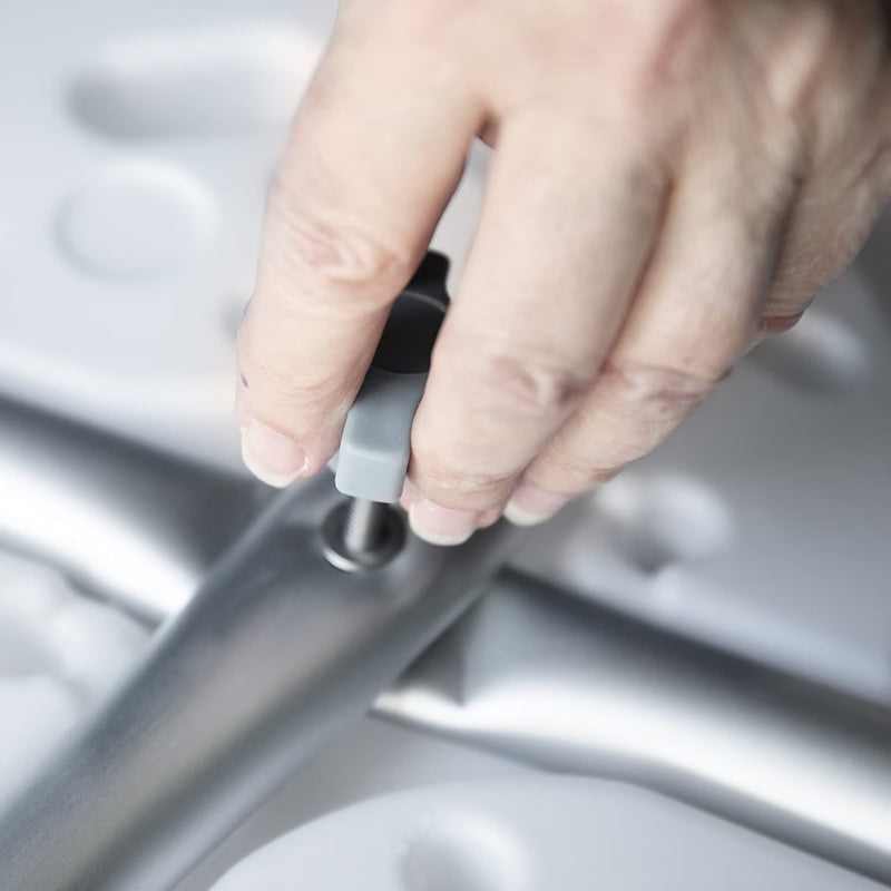 A close-up of a person's hand adjusting a gray and black plastic component on a silver metal frame.