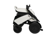 A compact electric wheelchair shown from a side profile view against a solid white background. The wheelchair features a white body shell with black accents, a black seat, and large black wheels.