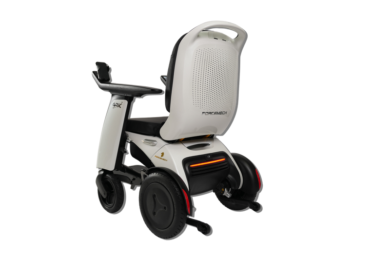 A modern power wheelchair shown from a three-quarters rear angle on a solid white background. The wheelchair features a white and black frame, a high backrest with a textured back panel, black wheels, and a small orange LED light indicator on the rear.