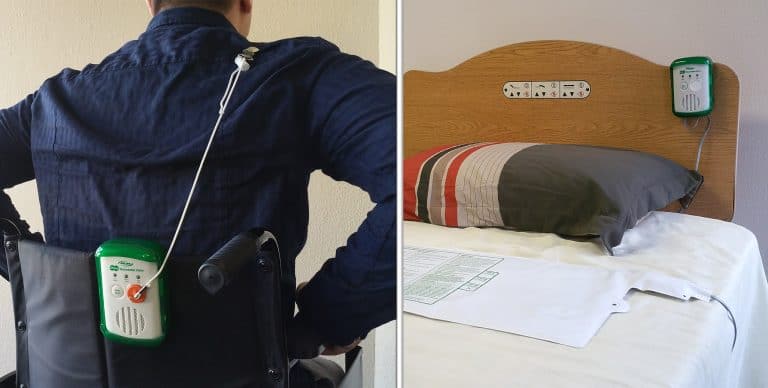 Person using a wheelchair with a medical device attached, next to a hospital bed with a pillow and blanket.