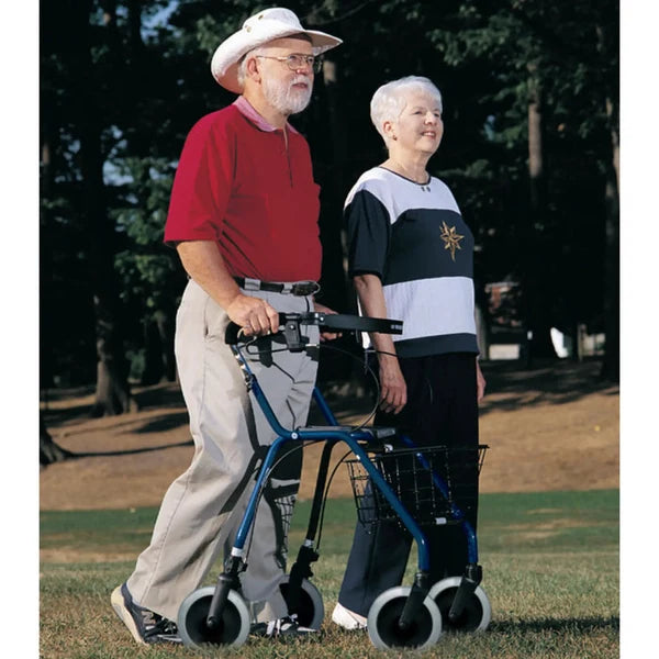 An elderly man wearing a white cowboy hat uses a blue four-wheel walker with a front basket while walking beside an elderly woman in a park.