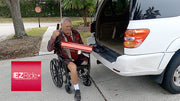 Man using a wheelchair with a ramp attached, loading into a white van.