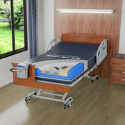 An electric hospital bed with a dark blue mattress, white side rails, and a wooden headboard, shown in a fully furnished bedroom setting with a window, curtains, and a wooden wall.