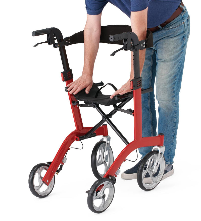 A red and black rollator walker with a seat and armrests, shown with a person in a blue shirt and jeans adjusting the seat and backrest against a white background.