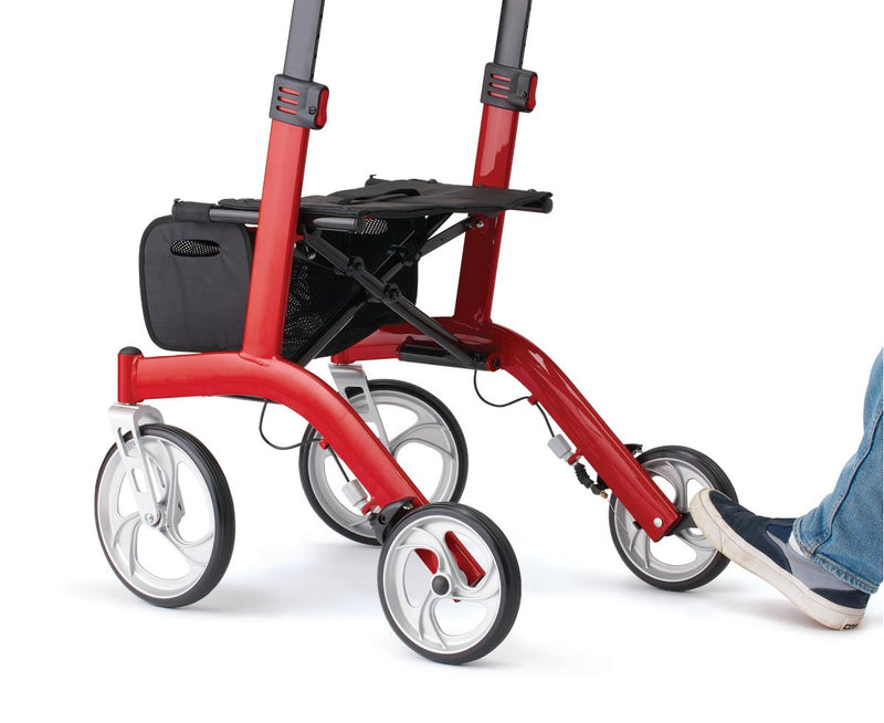 A red and black four-wheel rolling walker with a black storage basket, shown on a white background with a person's foot pushing one of the wheels.