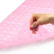 A hand peeling back a translucent pink bubble mat to show its flexible, textured surface on a white background.