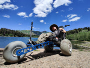 Person using a specialized vehicle near a lake with mountains in the background