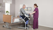 Person using a patient lift with a healthcare professional assisting them.