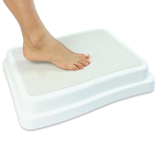 White step stool with a foot on it against a white background