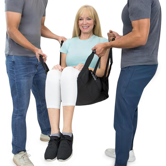 Woman being assisted into a black chair by two people on a white background