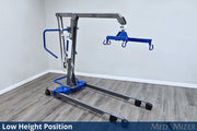 Medical lift device in a room with wooden flooring and white walls.