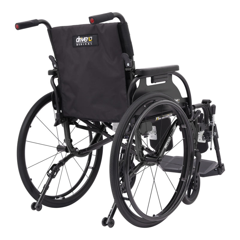 A black manual wheelchair with a padded backrest, shown from a three-quarter rear angle on a plain white background. The backrest features a visible 'drive2 history' logo patch.