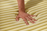 Hand pressing into a yellow foam mattress