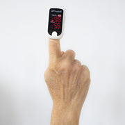 Hand with a finger inserted into a digital oximeter on a white background