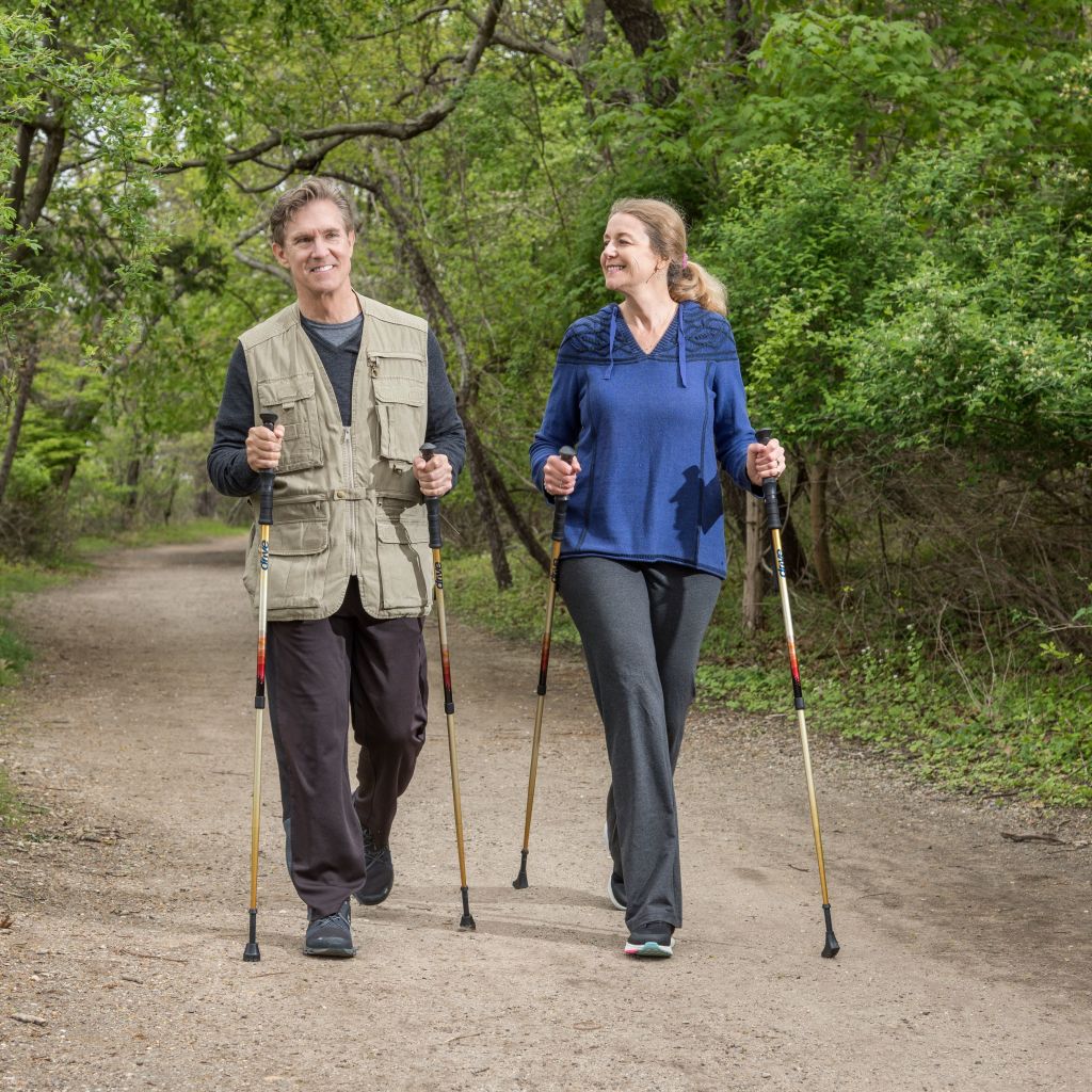 Two people nordic walking on a trail in a forested area