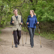 Two people nordic walking on a trail in a forested area
