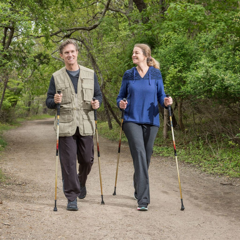 Two people nordic walking on a trail in a forested area