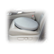 A round gray car seat cushion placed on a light beige car seat, shown inside a vehicle with a blurred white vignette around the edges.