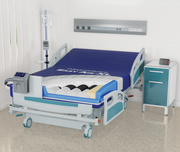 An electric hospital bed with a blue mattress and white/teal frame, shown in a clean clinical room with a side table, IV pole, and wall-mounted medical panel.
