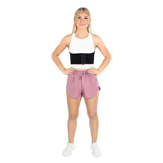 Woman wearing a white tank top with black accent and pink shorts on a white background