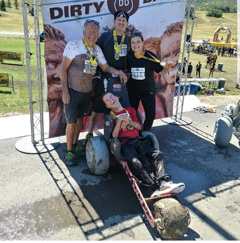 People posing with a decorated cart at an outdoor event, with a 'DIRTY DD' banner in the background.