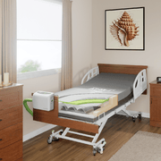 An electric hospital bed with a wood headboard and side rails, shown in a bedroom setting with a window, curtains, a dresser, and wall art.