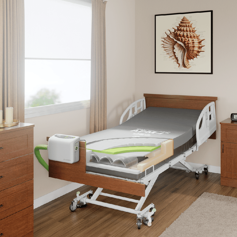 An electric hospital bed with a wood headboard and side rails, shown in a bedroom setting with a window, curtains, a dresser, and wall art.