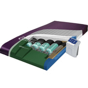 A 3D-rendered view of a SleepGuard Custom Care mattress treatment system, showing a purple and green mattress with teal and black gel packs, a blue support frame, and a white remote control on a plain white background.