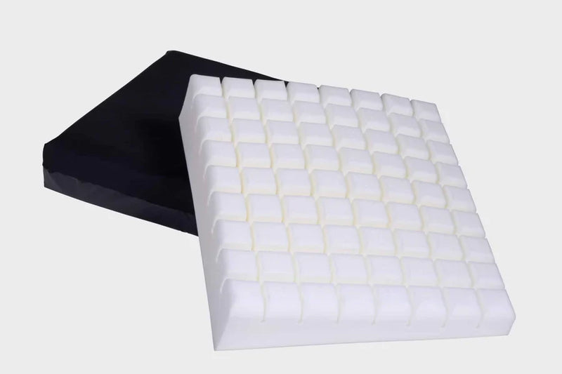 Two square foam or cushion-like pads shown on a plain light gray background, with one white pad in front and one black pad behind it.