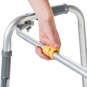 Hand holding a yellow handle on a silver walker against a white background